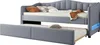 A gray upholstered daybed with a pull-out trundle bed underneath, set against a white background. The daybed has a tufted headboard and is adorned with decorative pillows and a folded blanket. Náhled obrázku produktu