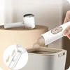 A hand is shown emptying lint from a fabric shaver into a trash can, with another fabric shaver in the background. Náhled obrázku produktu