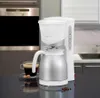 A white and silver coffee maker with a thermal carafe sits on a dark countertop, with a cup of coffee and some coffee beans nearby. A stainless steel oven is visible in the background. Anteprima dell’immagine prodotto