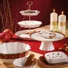 A festive Christmas table setting with a tiered cake stand, candles, pomegranates, and cookies. Anteprima dell’immagine prodotto