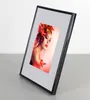 A framed photo of a woman with autumn leaves in her hair is displayed on a surface. Produktbild-Vorschau
