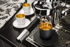 Espresso cups and an espresso machine are shown on a black countertop. Náhled obrázku produktu