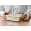 Hands holding a lunchbox on a wooden table. Anteprima dell’immagine prodotto