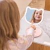 A young girl is looking into a cat-shaped mirror. Voir les images du produit