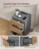 A gray nightstand with three open drawers, displaying its contents and features. The top surface shows a charging station with a phone and alarm clock. Produktbild-Vorschau
