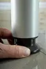 A hand is shown adjusting the foot of a silver cylindrical object, likely a piece of furniture, resting on a tiled floor. Anteprima dell’immagine prodotto