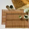 A top-down view of bamboo placemats with tea set accessories. Produktbild-Vorschau