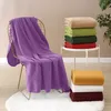 A purple blanket draped over a chair, with stacks of blankets in various colors on a small table and on the floor. Produktbild-Vorschau