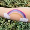 A rainbow painted on an arm with clouds on either side, set against a blurred green leafy background. Voir les images du produit