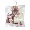 A doll clothing set is displayed in its clear plastic packaging, hanging on a hanger. Produktbild-Vorschau