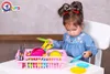 A young girl is playing with a toy kitchen set, specifically a dish rack with various colorful toy dishes and utensils. Náhľad obrázku produktu