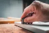 A close-up shot of a hand holding a tool and working on a piece of wood. Produktbild-Vorschau