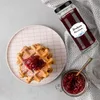 A waffle with jam and a jar of jam next to it. Produktbild-Vorschau