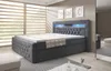 A modern bedroom with a large grey upholstered box spring bed. Produktbild-Vorschau
