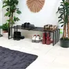 A shoe rack with various shoes placed on it, surrounded by plants. Podgląd zdjęcia produktu