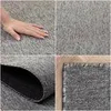 A collage of four images showing a gray rug from different angles, including a hand touching it, a close-up of the texture, and the underside. Produktbild-Vorschau