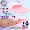 A collection of children's nail art supplies, including nail dryers, polish, and accessories, arranged around a child's hand. Produktbild-Vorschau