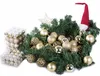 A collection of gold and silver Christmas ornaments arranged with evergreen branches and a gnome hat. Anteprima dell’immagine prodotto