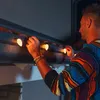 A man is hanging Christmas lights on the gutter of a house. Náhled obrázku produktu