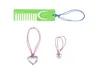 A green comb with a blue string and two pink necklaces with heart pendants are displayed against a white background. Produktbild-Vorschau