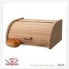 A wooden bread box with a roll-top lid and a small bread roll in front of it, set against a white background. There is a logo and text at the bottom. Produktbild-Vorschau