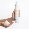 A hand holding a bottle of Milk_Shake Whipped Cream leave-in foam, with some foam dispensed into the palm of the hand. Anteprima dell’immagine prodotto