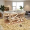 A wooden hamster cage filled with hamsters, placed on a bed of straw in a living room setting. Produktbild-Vorschau