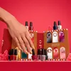 A hand with gold nail polish is reaching towards an open advent calendar shaped like a gingerbread house, filled with OPI nail polish bottles. Anteprima dell’immagine prodotto