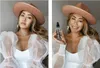 A split image showing a woman wearing a hat and a white dress, holding a bottle of tanning mist in the right panel. Produktbild-Vorschau