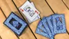 A deck of playing cards and several loose cards are spread out on a wooden surface. Produktbild-Vorschau
