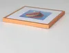 A framed picture with a rainbow-colored object against a blue background, placed on a white surface. Produktbild-Vorschau