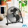 A black floor fan is placed on a light-colored floor in a room with plants and natural light. Voir les images du produit