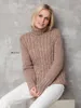 A woman is sitting and posing in a knitted sweater. Produktbild-Vorschau