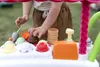 A child's hands are playing with a toy ice cream cart outdoors. Anteprima dell’immagine prodotto