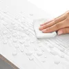 A hand is wiping water droplets off a white wooden surface with a white cloth. Produktbild-Vorschau