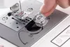 A close-up shot of a person's hand inserting a bobbin into a sewing machine. Produktbild-Vorschau