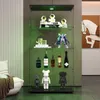 A glass display cabinet with various items on shelves, including figurines, books, and bottles, illuminated by green LED lights. Podgląd zdjęcia produktu