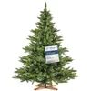 A green artificial Christmas tree with a wooden stand and a quality certification tag. Podgląd zdjęcia produktu