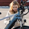 A young woman wearing gloves is adjusting an electric bicycle. Produktbild-Vorschau