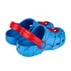A pair of blue Spider-Man themed clogs with red straps, shown from a diagonal angle against a white background. Produktbild-Vorschau