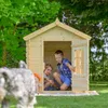 Two boys playing in a wooden playhouse in a garden, with a blurred dog in the foreground. Anteprima dell’immagine prodotto