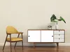 A yellow chair and a wooden cabinet with white drawers and doors are placed on a wooden floor against a cream-colored wall. Produktbild-Vorschau