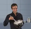 A man is in a kitchen, whisking ingredients in a bowl. Anteprima dell’immagine prodotto