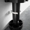 A close-up view of a black plastic cabinet leg with a white clip attached to a white wall. Produktbild-Vorschau