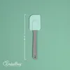 A light green background with a turquoise and gray spatula in the center. A measurement line and text are on the left side, and a logo is in the bottom left corner. Anteprima dell’immagine prodotto