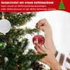 A person is decorating a Christmas tree with red and white ornaments. Náhľad obrázku produktu