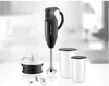 An immersion blender and its accessories are displayed on a white surface with a blurred background. Náhľad obrázku produktu