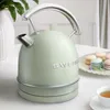 A pastel green electric kettle is shown on a table with macarons and a cup of tea. Produktbild-Vorschau