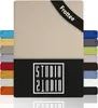 A product image showing a beige fitted sheet with a black band at the top displaying the text 'Frottee'. To the left and right of the main sheet are stacks of smaller sheets in various colors, showcasing the available color options. Below the main sheet is Produktbild-Vorschau
