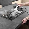A person is using a handheld steam cleaner to clean a gas stove. Produktbild-Vorschau